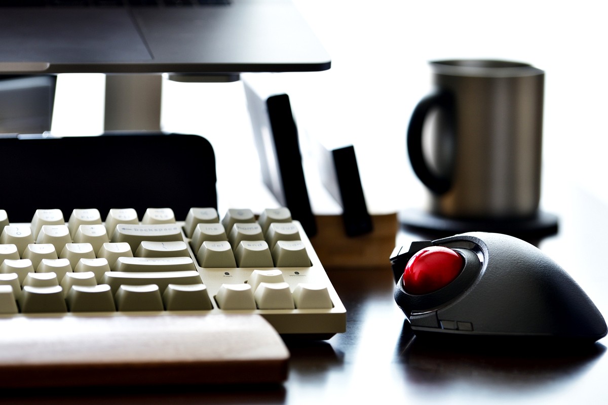 デスク上のキーボード・トラックボール・マグカップの作業環境